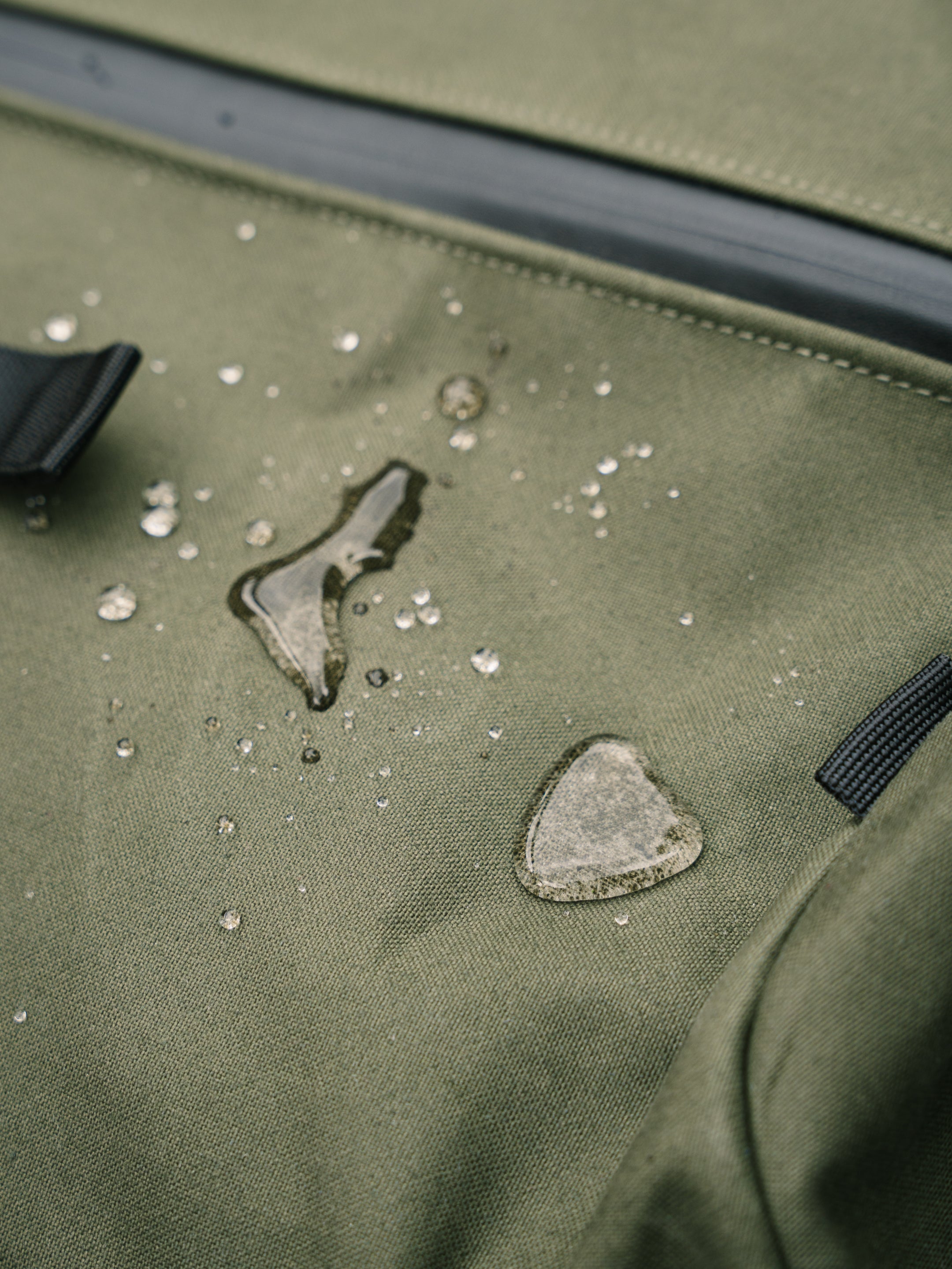 Water beading on the water-resistant fabric of the Bridge Backpack in Khaki Green