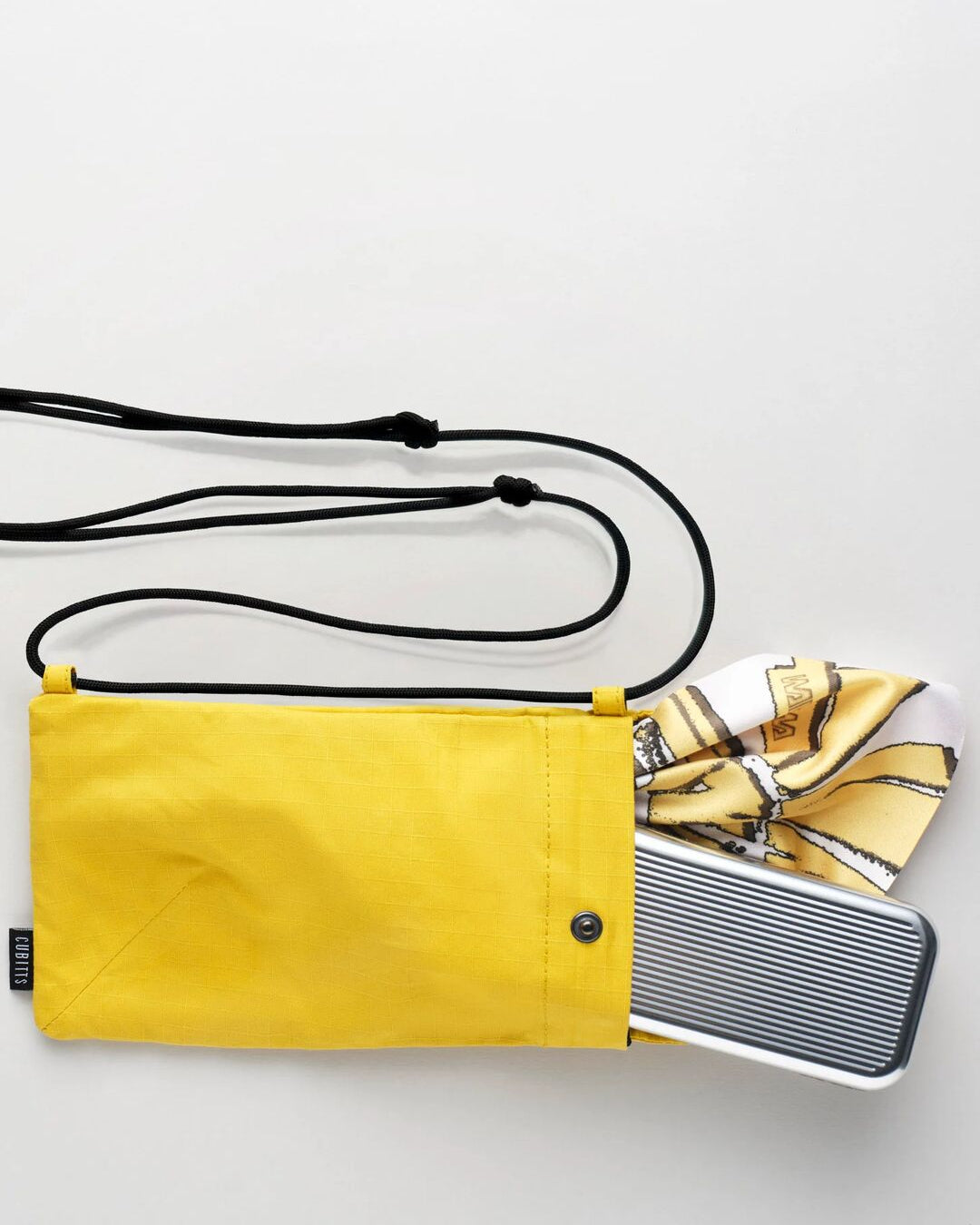 Yellow Sunnies Sling holding a tin and lens cloth, showing capacity
