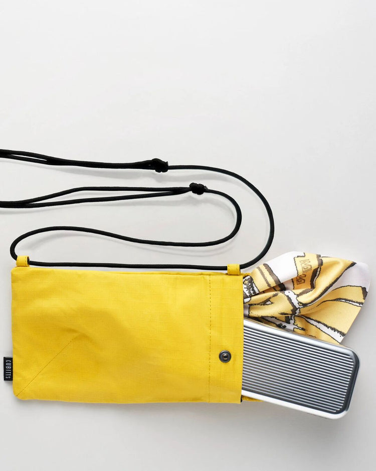 Yellow Sunnies Sling holding a tin and lens cloth, showing capacity